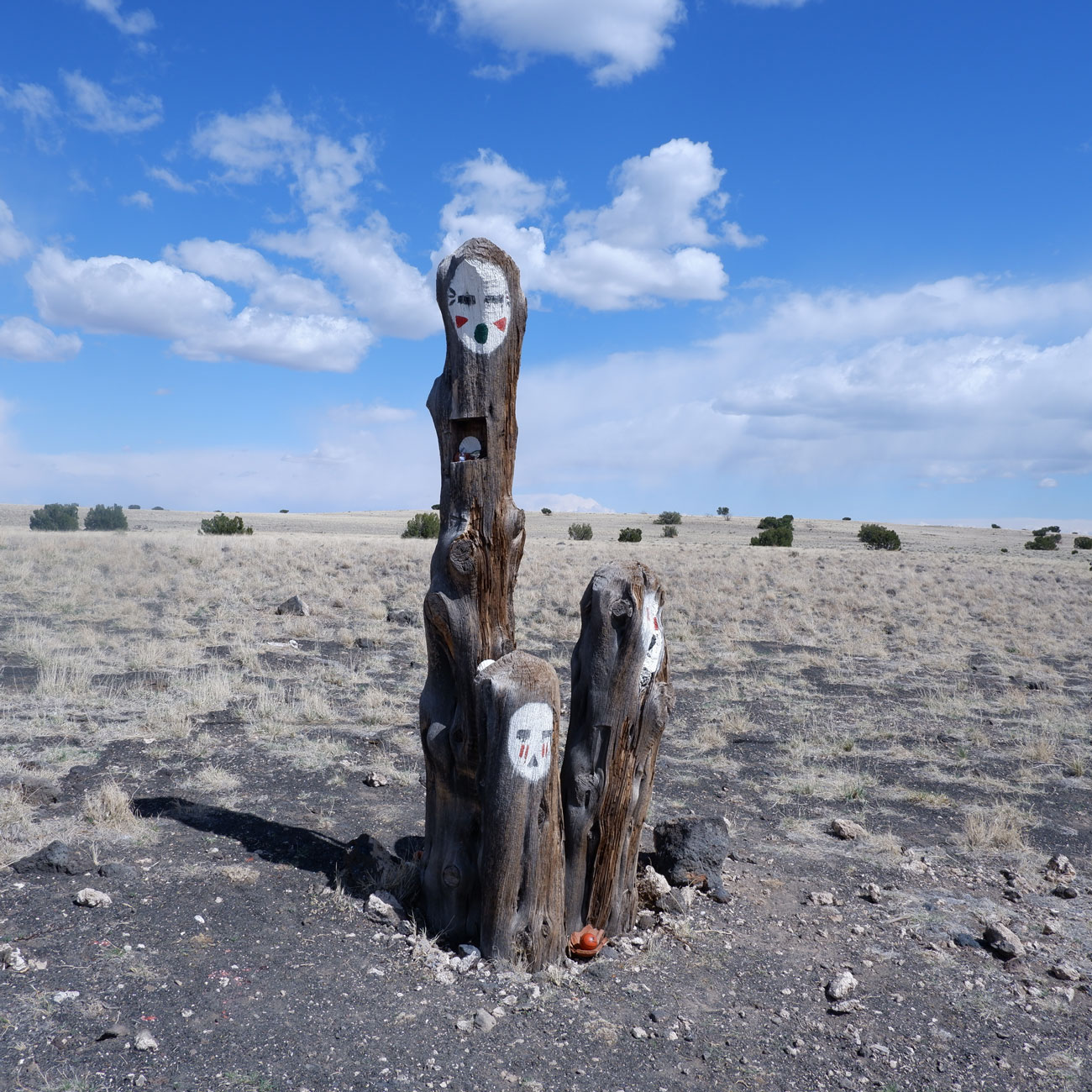 A photo of a sculpture in the high desert with a blue sky and clouds behind.