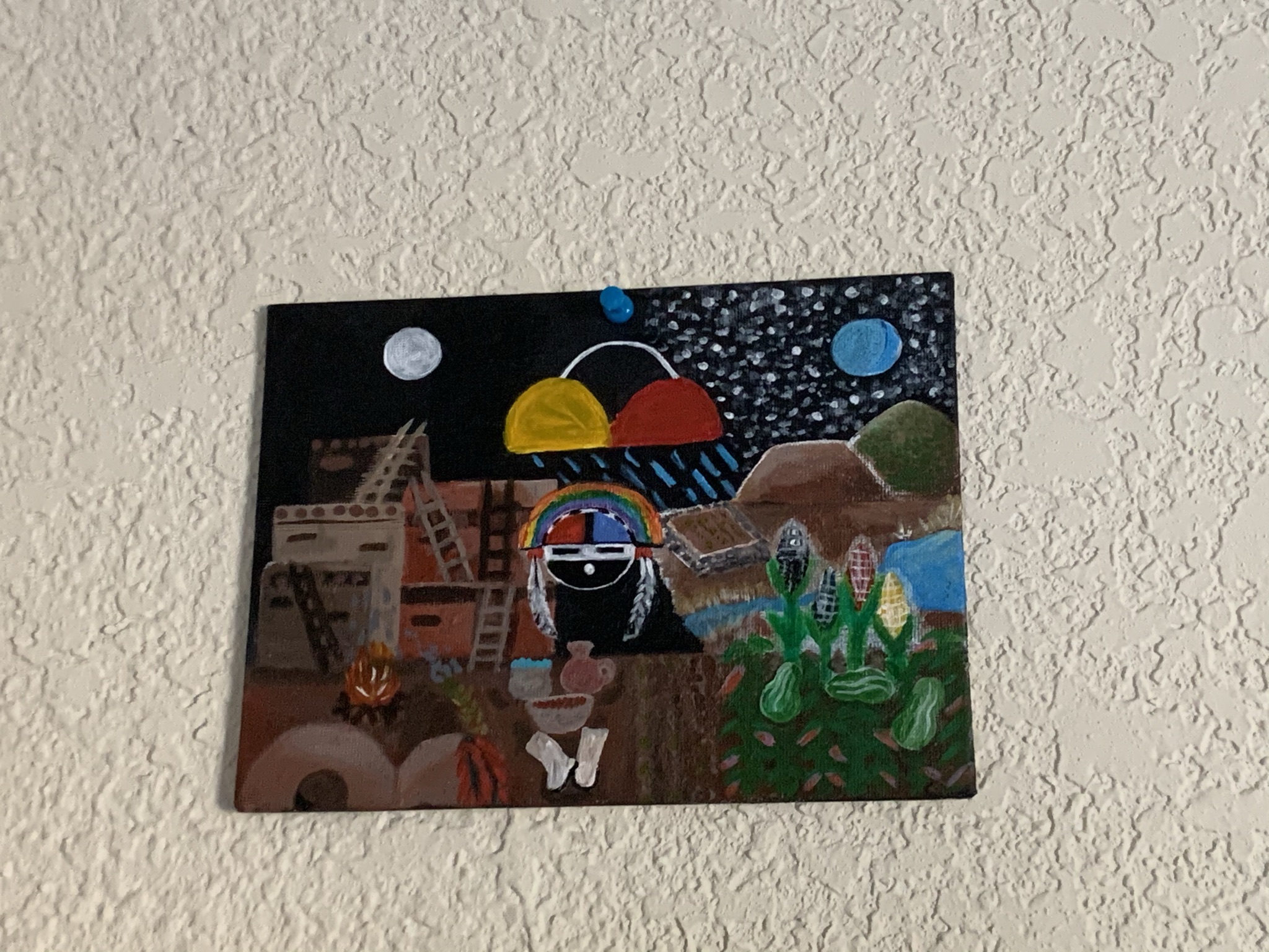A photograph of a painting. It is a black background with a white moon on one side and blue on the other. Pueblo buildings like those in Taos are in the background, rain falls from the center. Three sisters crops are on the other corner opposite the buildings and in the center a singing person.