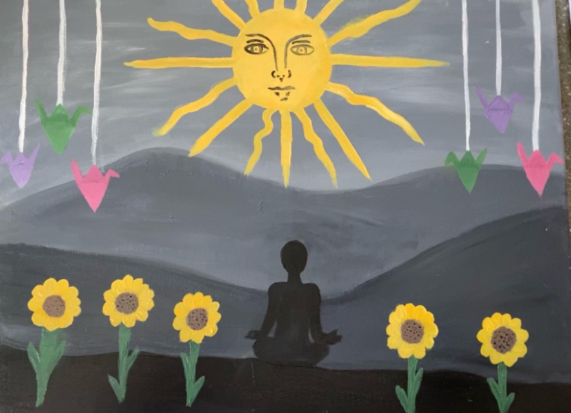 A painting depicting the silhouette of a person sitting cross legged surrounded by bright sunflowers. The background is black and grey hills and a gray sky with a bright, yellow sun with two eyes, a nose, and lips. 3 paper cranes on string are painted on either side of the sun.